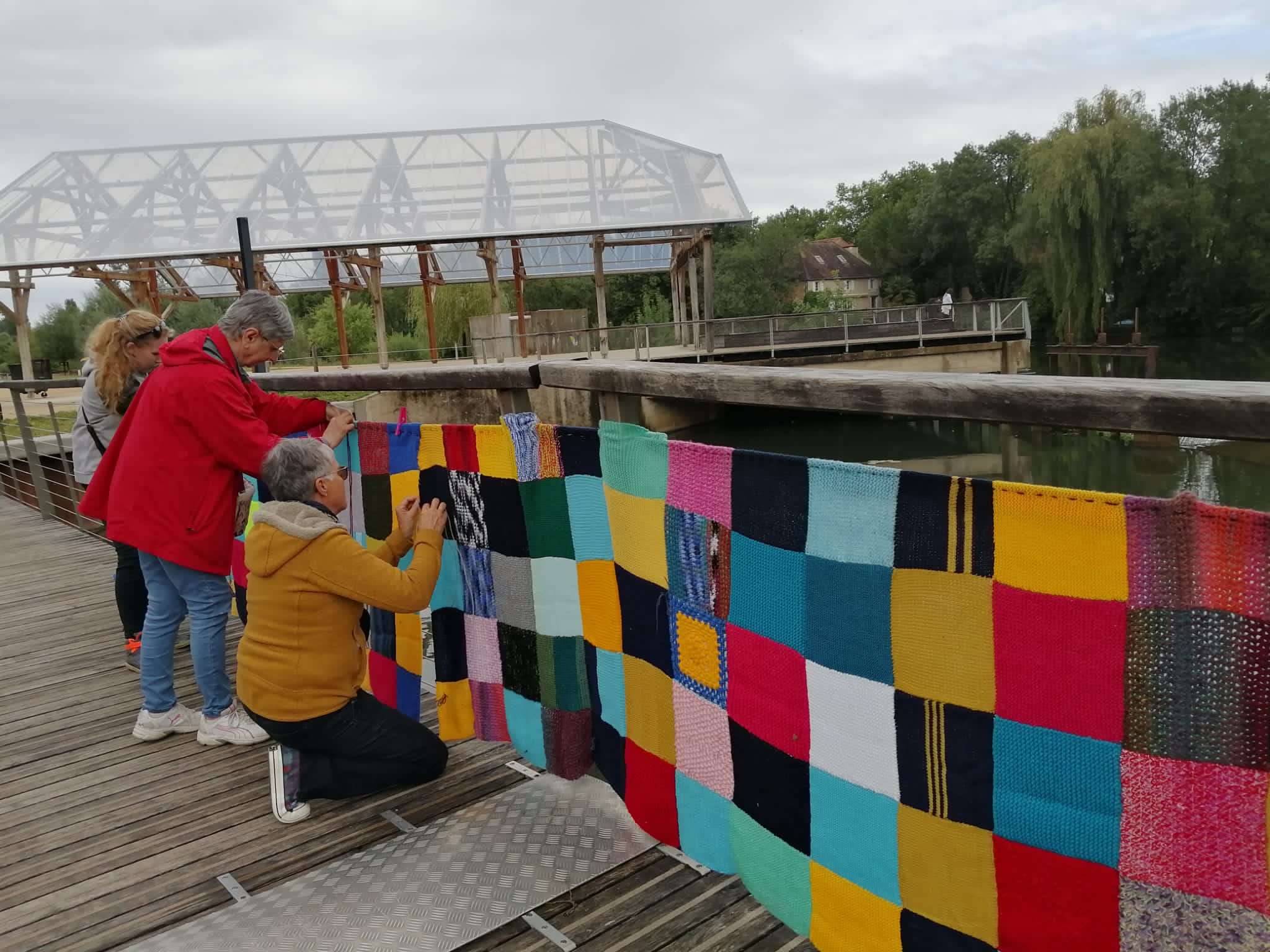Photo de femmes accrochant une couverture tricotée sur un pont