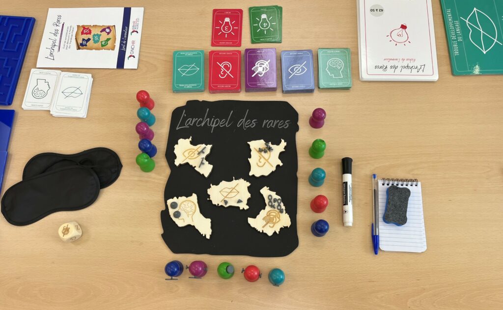 Photo du contenu du jeu exposé sur une table : plateau de jeu, pions, cartes, livret de l'animateur